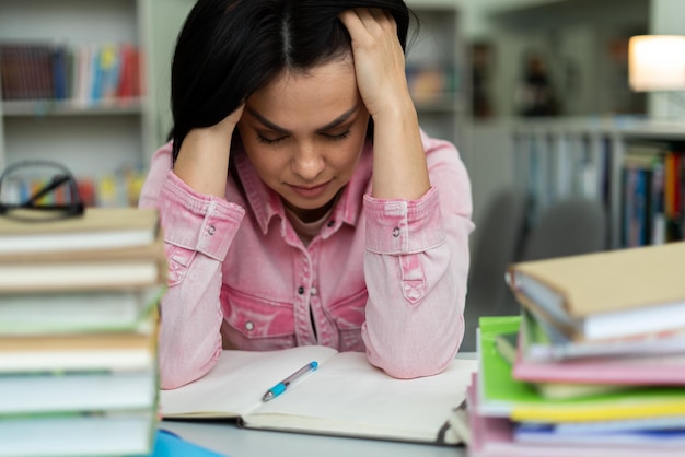 College student suffering from headache in classroom troubled\
and stressed girl doing exam that doesn\'t know the answers