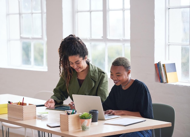 Foto studenti universitari che lavorano insieme due giovani donne amiche di brainstorming idee per il progetto seduti alla scrivania utilizzando il computer portatile in classe