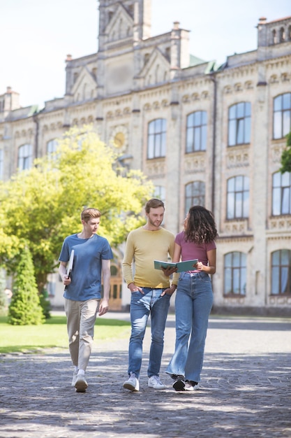 College tuin. drie studenten lopen op het schoolplein en praten