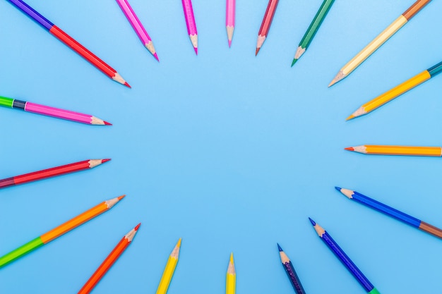 Collor wooden pencils in row isolated on bluebackground. Top view with copy space.