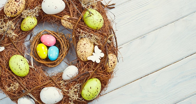 Coloeful paaseieren in nest op roze kleur achtergrond met ruimte Minimaal concept kaart met kopie ruimte voor tekst