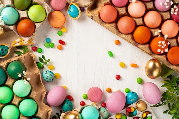 Colofrul Easter eggs and scattered candies on wooden table