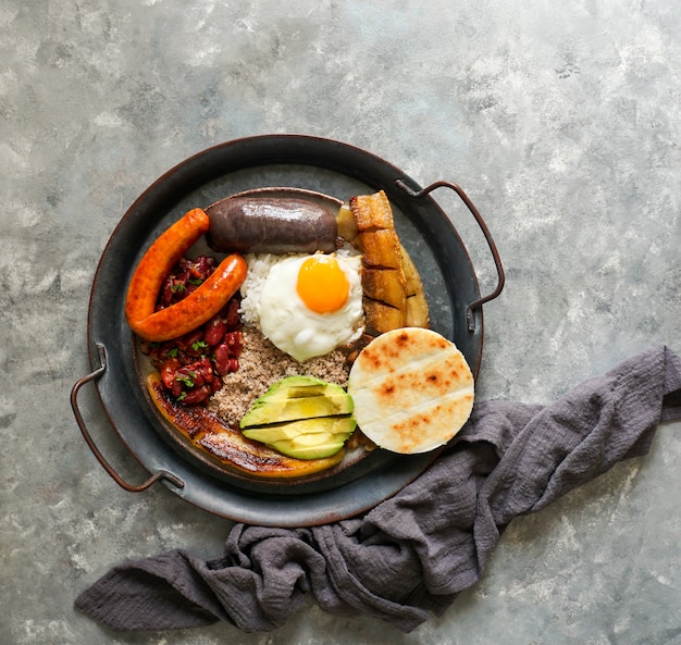 Colombiaans eten. Bandeja paisa, typisch gerecht in de regio Antioquia in Colombia - chicharron (gebakken buik van varkensvlees), bloedworst, worst, arepa, bonen, gebakken weegbree, avocado-ei en rijst.