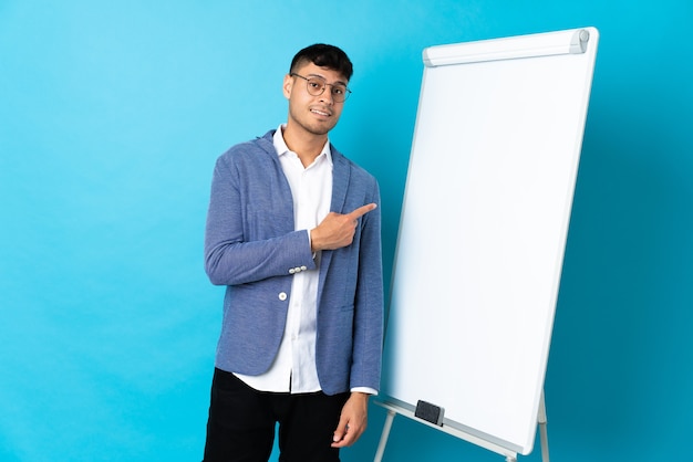 Colombiaanse man die een presentatie geeft op wit bord en naar de zijkant wijst