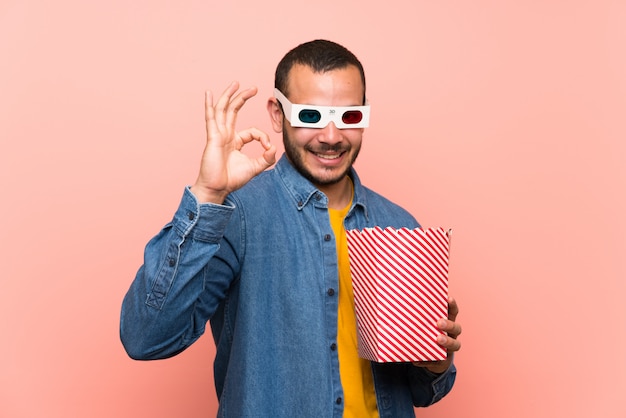 Colombiaanse mens met popcorns die een ok teken met vingers tonen