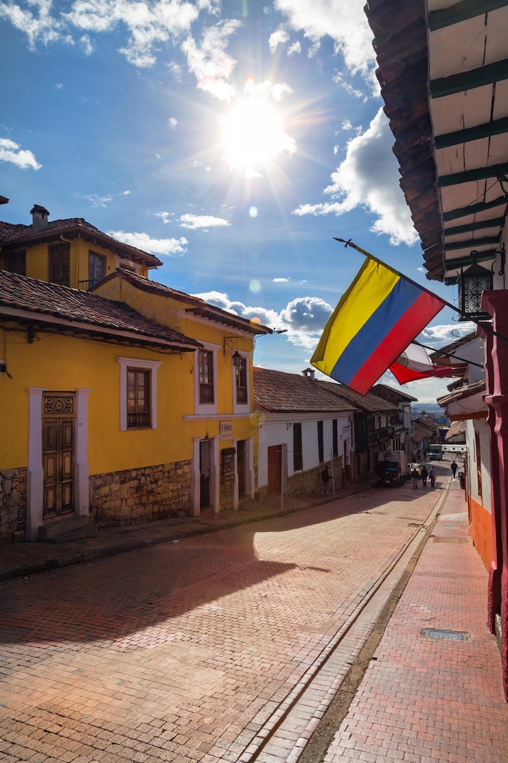 Photo colombian flag flies over a cobblestone street in the candelaria neighborhood of bogota colombia