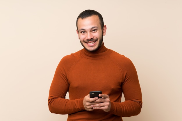 Colombian man with turtleneck sweater sending a message with the mobile