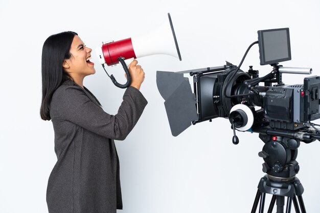 Colombian reporter woman holding a microphone and reporting news on white wall shouting through a megaphone