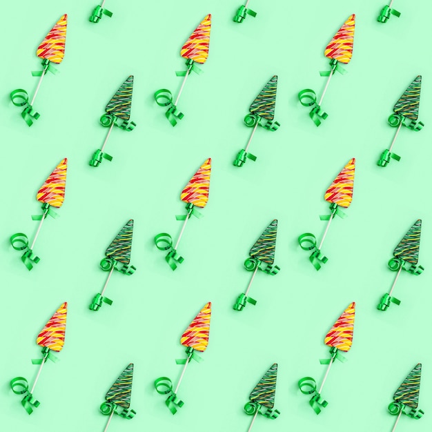 Color candy creative seamless pattern for New Year or Christmas. Lollipops shaped like Christmas tree on green background.