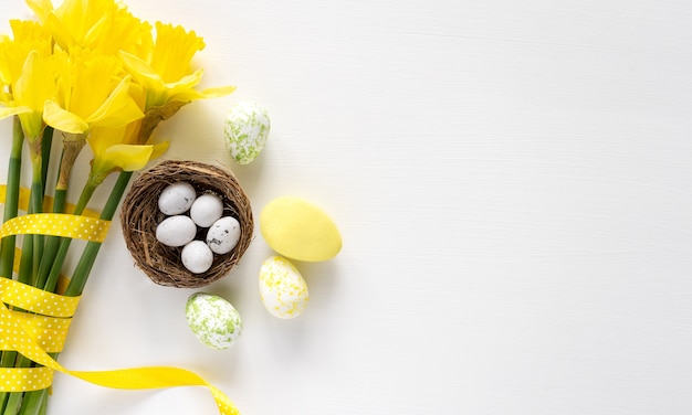 Color egg easter and yellow flowers bouquet on white background, copy space, top view, greeting card. Easter background