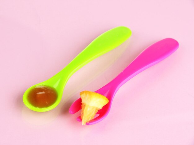 Фото Цветная вилка и ложка для детского питания на розовом фоне