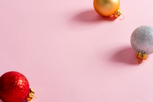 Color full christmas ball Ornaments hanging on pink background. minimal christmas concept.