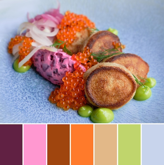 Tavolozza di colori abbinati dall'immagine di piccole frittelle servite con cipolle di insalata di barbabietole rosse di caviale di salmone e salsa di pere verdi