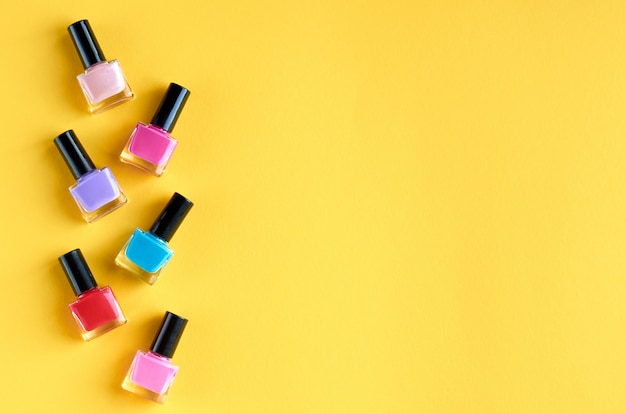 Color nail polish bottles on yellow surface.