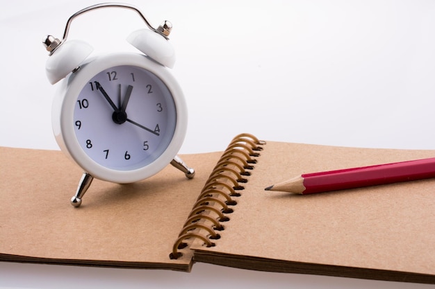 Color pencil and an alarm clock placed on a notebook