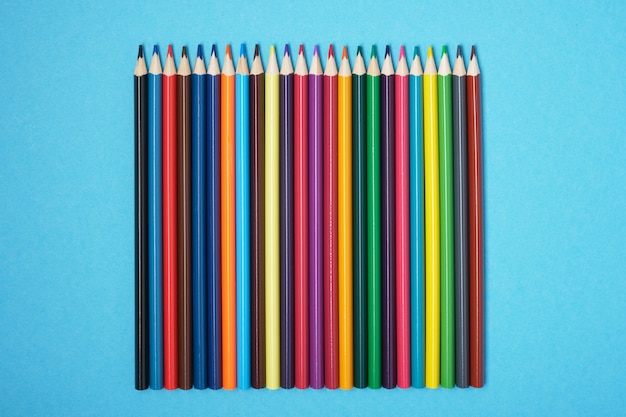 Color pencils on blue background copy space top view