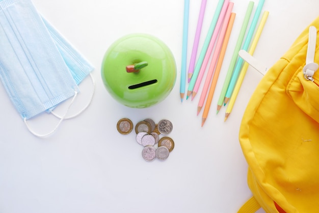 Color pencils face mask and coins on white background