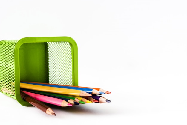 Цветные карандаши в зеленой корзине на белом фоне
