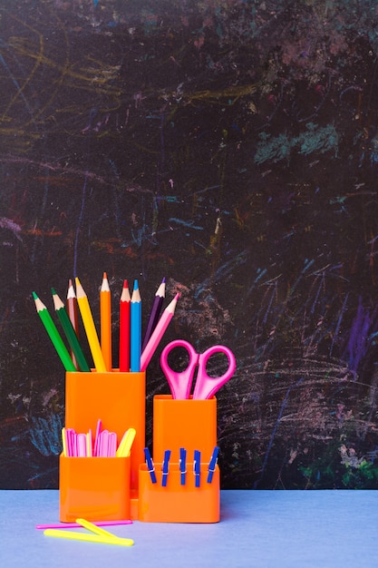 Цветные карандаши, ножницы, счетные палочки и зажимы в стакане для канцелярских товаров на столе