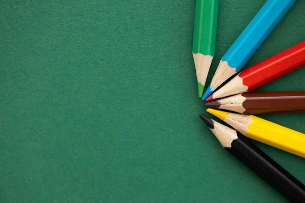 Color pencils with different color over green background