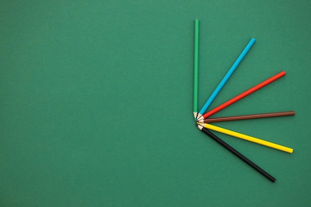 Color pencils with different color over green background