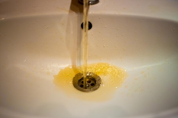 Foto fotografia a colori di un'acqua arrugginita che scorre da un rubinetto in primo piano acqua sporca dal rubinetto