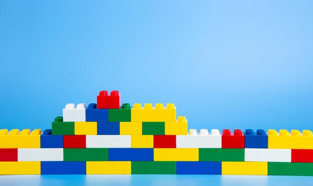 Color plastic building blocks on blue background