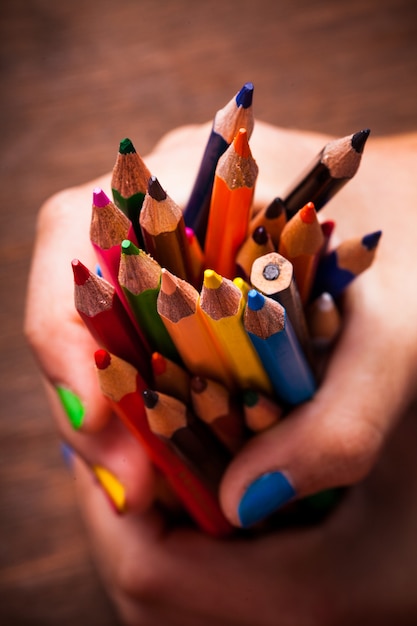 Цветные радужные карандаши и руки подростка с разноцветными ногтями