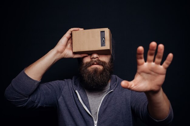 Color shot of a young man looking through a cardboard VR headset