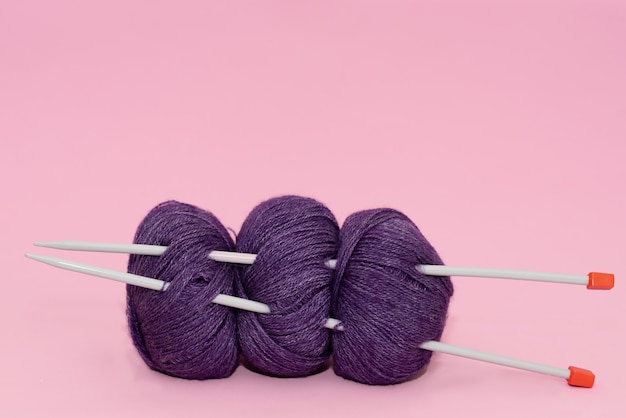 Color thread for knitting, knitted scarf, knitting needles on a dark background. 