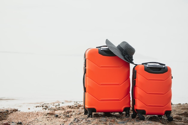 Color travel suitcase on sandy beach with turquoise sea