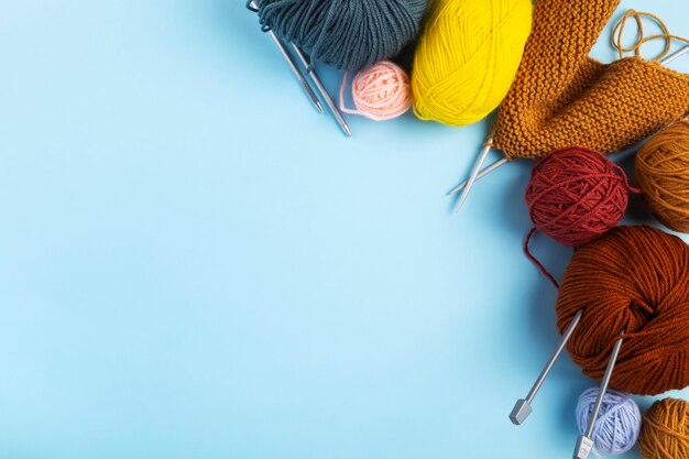 Color yarn for knitting, blue background. Knitting project in progress. Top view. Copy space