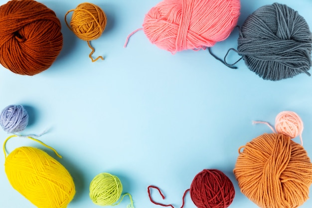 Color yarn for knitting, knitting needles and crochet hooks, blue background. Top view. Copy space