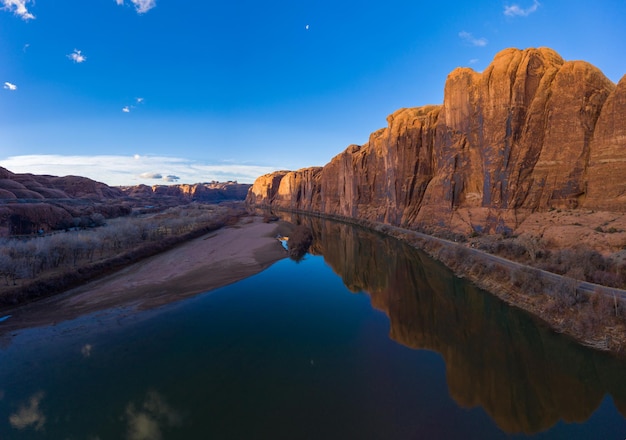 Colorado River and Red Sandstone Cliffs on Sunny Day. Wall Street Rock Climbing Area. Blue Sky Reflection in Water. Grand County, Utah, USA. Aerial View.