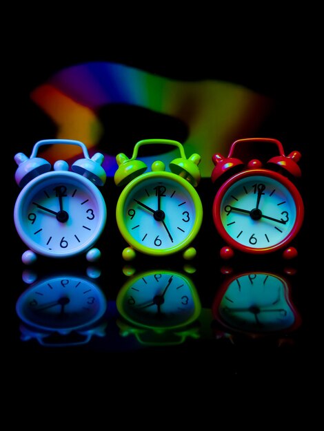 Colored alarm clock with colorful reflection on a black background