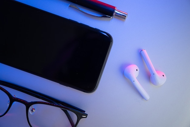 Photo on a colored background, laptop, glasses, pen, headphones, top view. business concept.