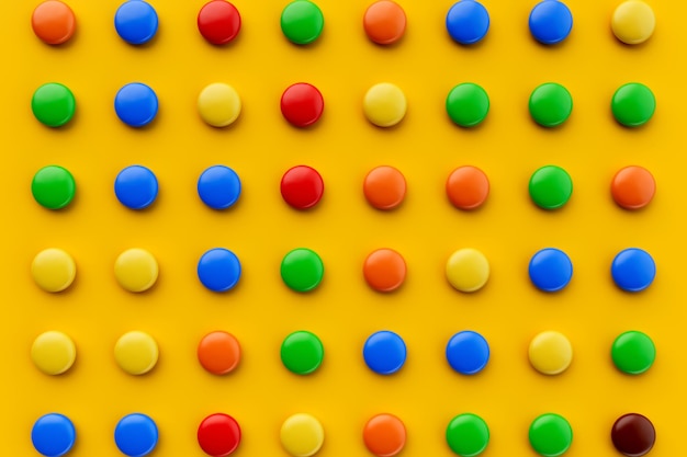 Photo colored balls of sugar on a yellow chocolate candies covered with multicolored sugar glaze 3d