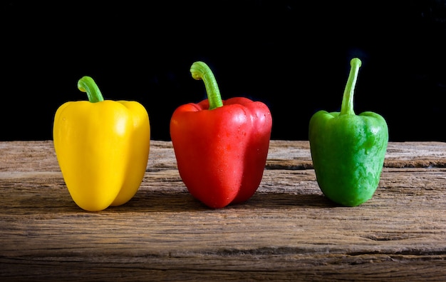 Colored bell peppers on wooden table