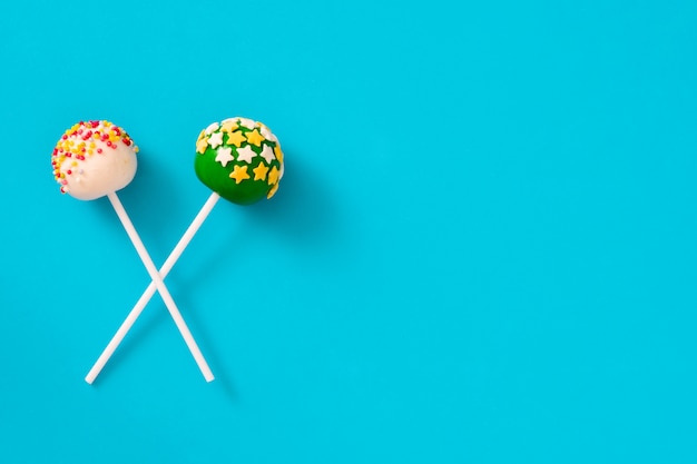 colored cake pops on blue background copy space