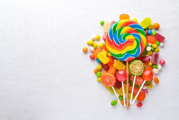 Colored candies sweets and lollipops On a white wooden background Top view Free space