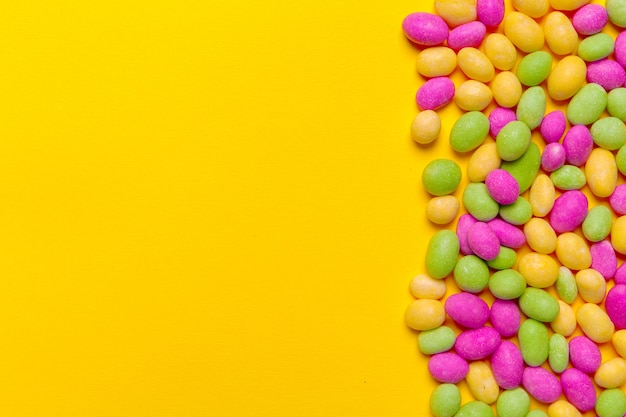 Colored candies on yellow background