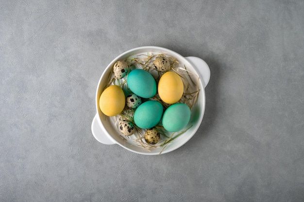 Colored chicken eggs and quail eggs in a white dish