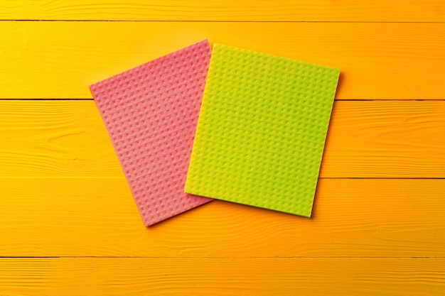 Colored cleaning rags on yellow wooden background