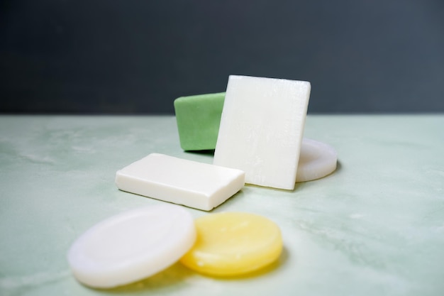 colored cleansing body wash soap bars lies in green stone surface against gray wall