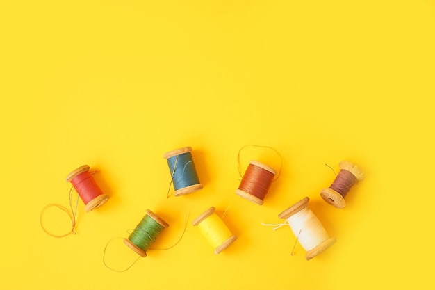 Colored coils with threads on a yellow backgroundHandicrafts and sewing Top view