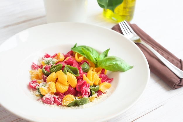 Colored conchiglie pasta with parmesan and basil