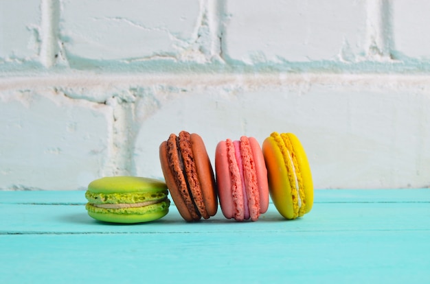 Colored cookies macaroons close-up on a table against a white brick wall background
