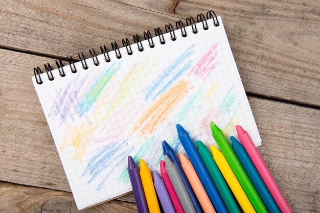 Colored crayons and blank page on the wooden table