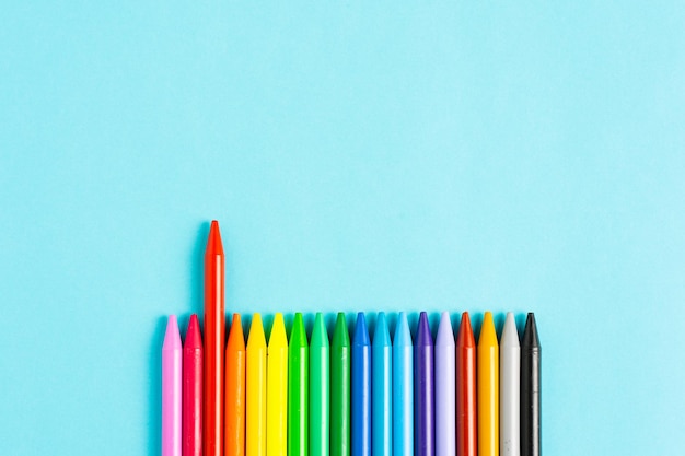 Colored crayons on blue background with copy space. A piece stands out over competence.