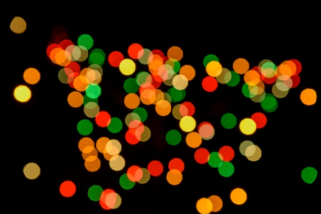 Colored defocused lights on dark background. Light bokeh.